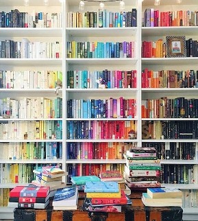 Una estantería llena de muchos libros sobre una pared blanca.